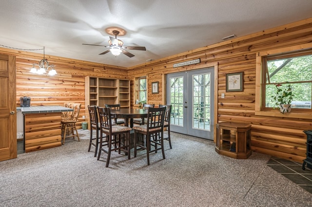 carpeted dining area with a wood stove, a textured ceiling, a ceiling fan, healthy amount of natural light, and french doors