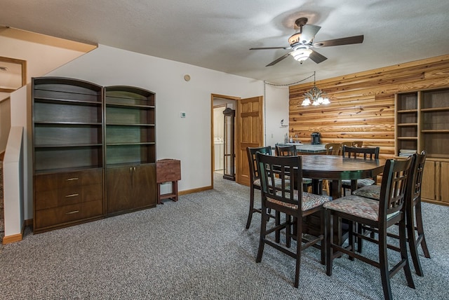 dining room featuring carpet floors, a ceiling fan, baseboards, rustic walls, and a textured ceiling