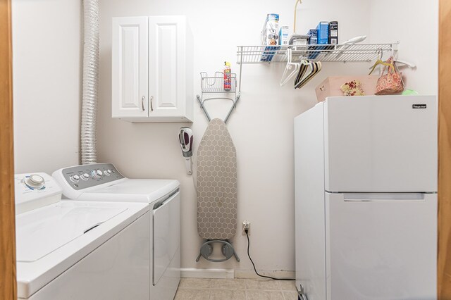 washroom featuring cabinet space, washer and dryer, light tile patterned floors, and baseboards