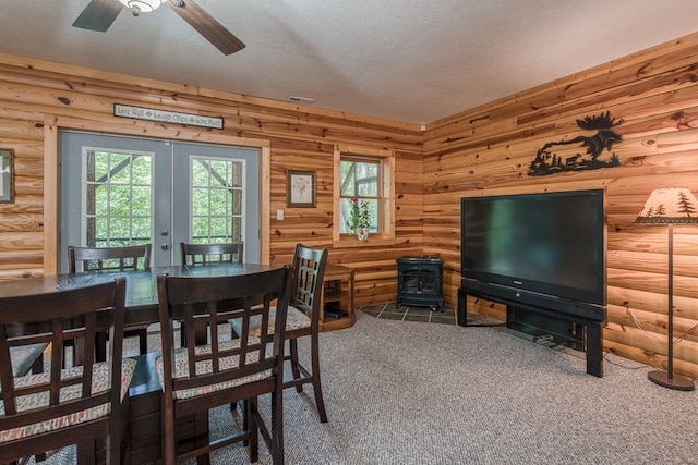 dining room featuring a wood stove, french doors, carpet, a textured ceiling, and a ceiling fan