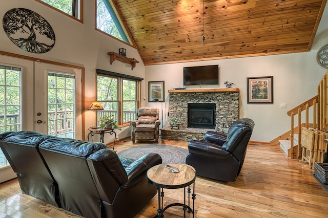 living area featuring high vaulted ceiling, stairs, wood ceiling, a fireplace, and light wood-style flooring