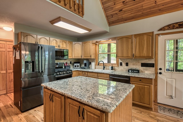 kitchen with appliances with stainless steel finishes, a sink, healthy amount of natural light, light wood-type flooring, and lofted ceiling