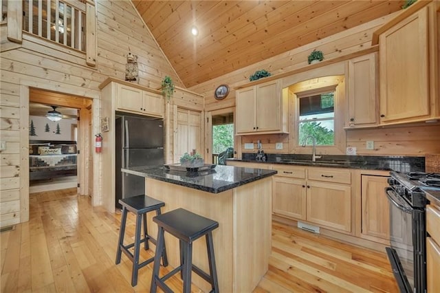 kitchen with light hardwood / wood-style flooring, wooden walls, gas range oven, and ceiling fan