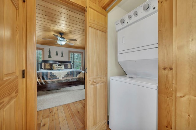 laundry area featuring stacked washing maching and dryer, light hardwood / wood-style floors, ceiling fan, and wood ceiling