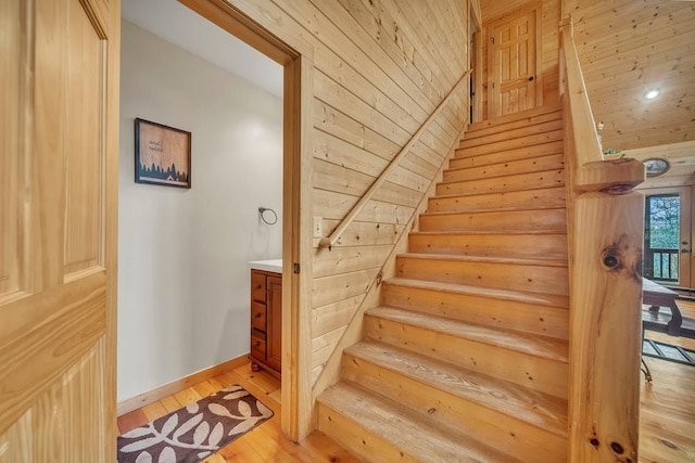 stairway with light hardwood / wood-style flooring, wooden walls, and wood ceiling