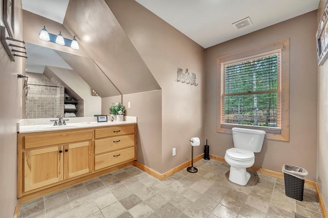 bathroom with lofted ceiling, tile flooring, toilet, and vanity