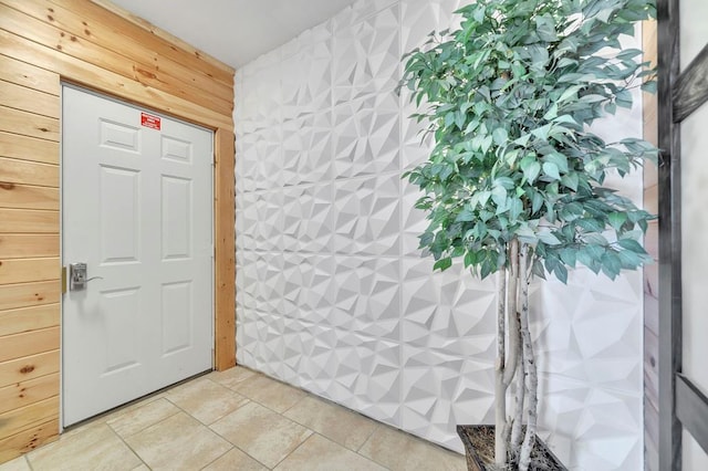 doorway to outside featuring wooden walls and light tile floors