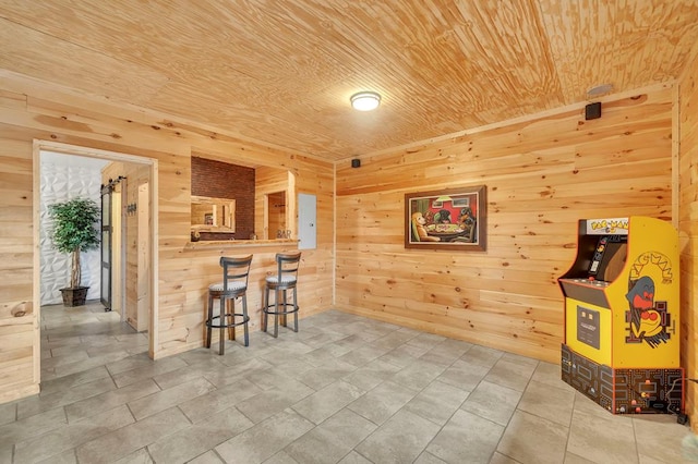 interior space with bar, wood ceiling, light tile flooring, and wood walls