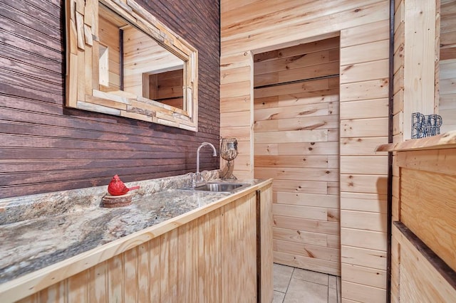 bathroom with wood walls, tile flooring, and sink