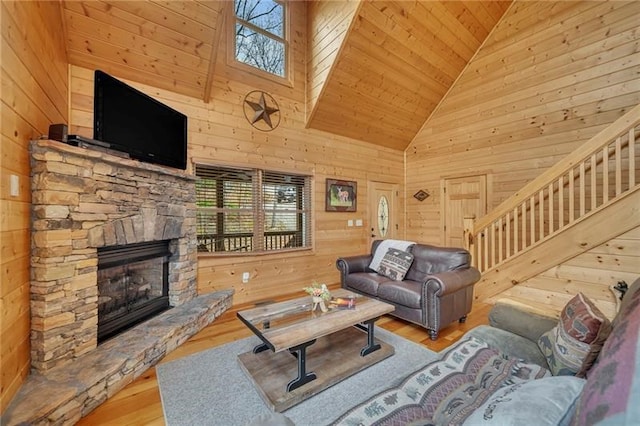 living room featuring wood walls, high vaulted ceiling, a fireplace, wood ceiling, and light hardwood / wood-style flooring