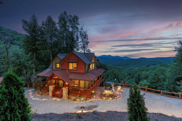 chalet / cabin featuring metal roof, covered porch, a forest view, and fence