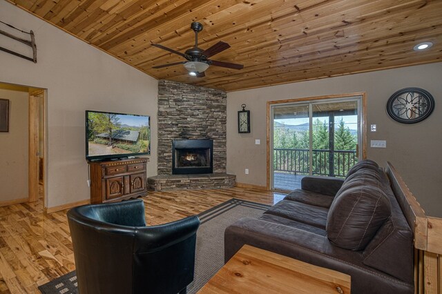 living room with a stone fireplace, a ceiling fan, wooden ceiling, wood finished floors, and lofted ceiling