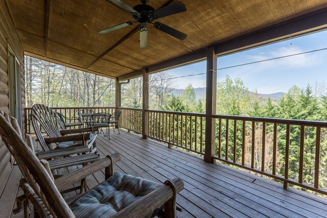 wooden terrace featuring outdoor dining area, a mountain view, and ceiling fan