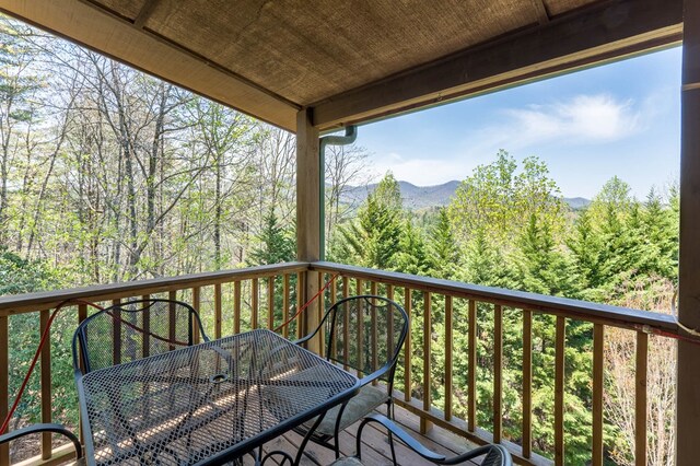 wooden deck featuring a forest view, a mountain view, and outdoor dining area