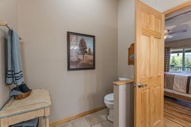 ensuite bathroom featuring baseboards, connected bathroom, ceiling fan, and toilet