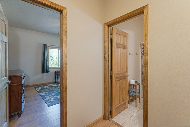 corridor featuring light wood-style floors and baseboards