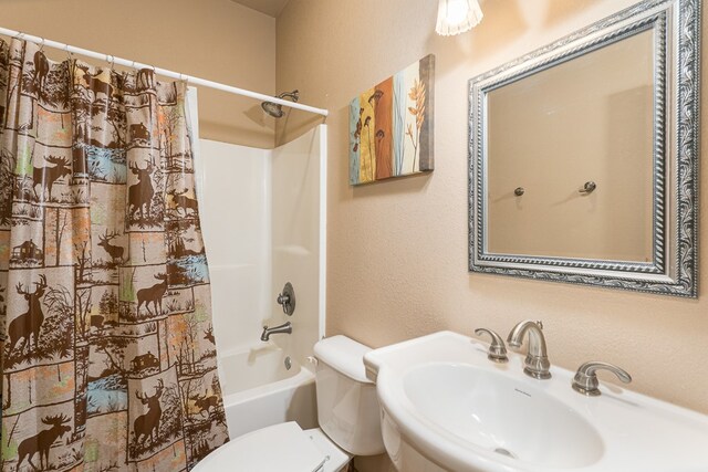 bathroom with a sink, a textured wall, shower / bath combination with curtain, and toilet
