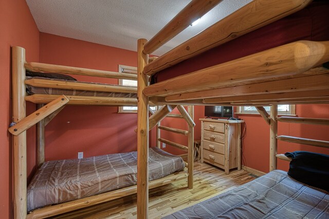 bedroom with baseboards, a textured ceiling, and wood finished floors