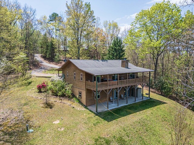 rear view of house with a lawn, a patio area, a wooden deck, and a chimney