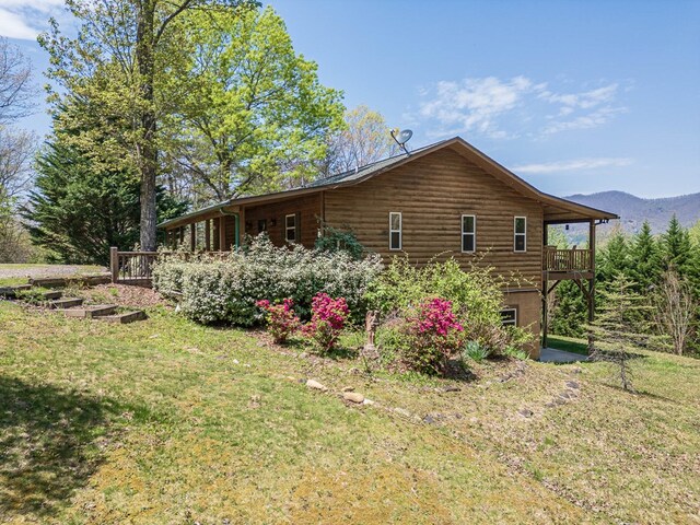view of side of property with a yard, a mountain view, and a vegetable garden
