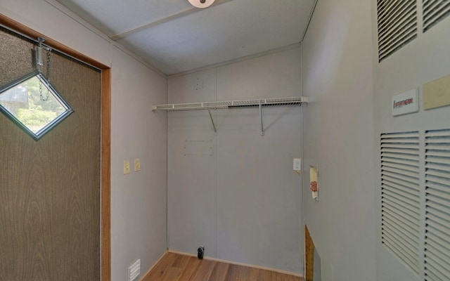 washroom with laundry area, wood finished floors, and a heating unit