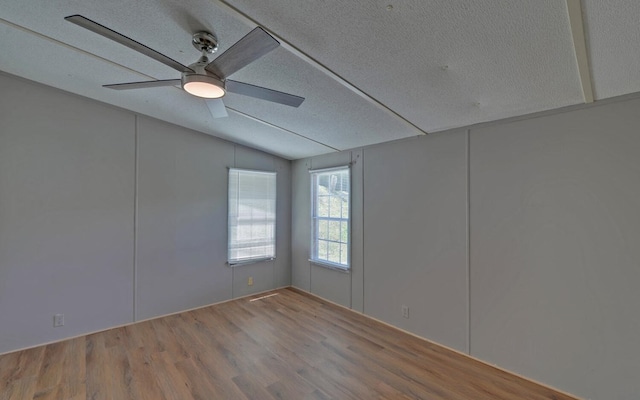 unfurnished room featuring ceiling fan, vaulted ceiling, a textured ceiling, and wood finished floors