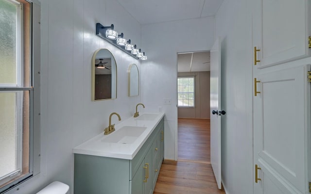 bathroom with double vanity, toilet, a sink, and wood finished floors