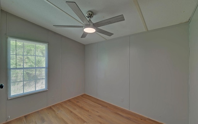 spare room with light wood-style floors, ceiling fan, a wealth of natural light, and vaulted ceiling