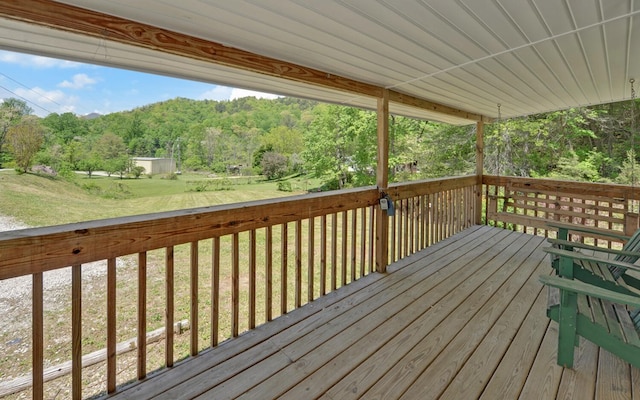deck with a lawn and a wooded view
