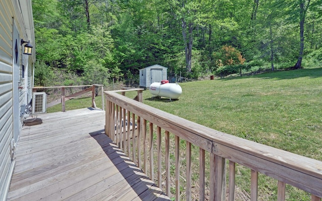 wooden terrace with a storage unit, central AC unit, a yard, and an outbuilding
