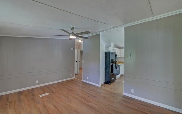 unfurnished room featuring a decorative wall, a ceiling fan, baseboards, wood finished floors, and ornamental molding