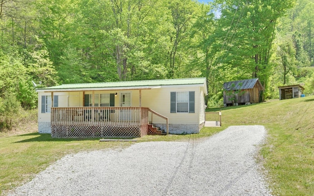 manufactured / mobile home with an outdoor structure, a shed, a front yard, covered porch, and metal roof