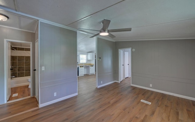 unfurnished room featuring crown molding, a decorative wall, a ceiling fan, wood finished floors, and visible vents