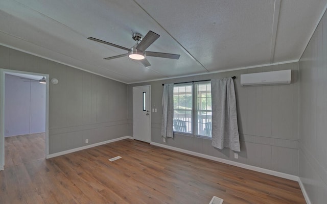 empty room featuring wood finished floors, a ceiling fan, baseboards, and a wall mounted AC