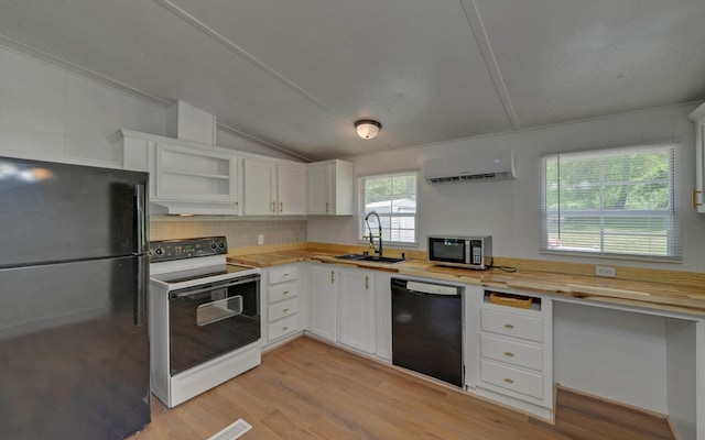 kitchen with a sink, a wall mounted air conditioner, white cabinetry, vaulted ceiling, and black appliances