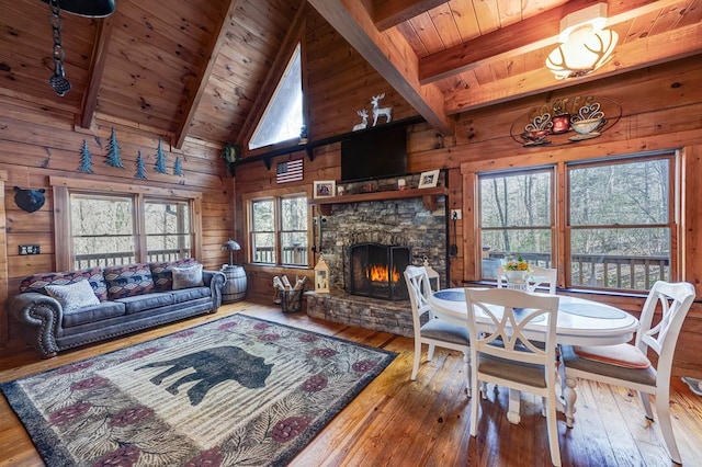 living room featuring wood ceiling, a stone fireplace, hardwood / wood-style flooring, and wood walls