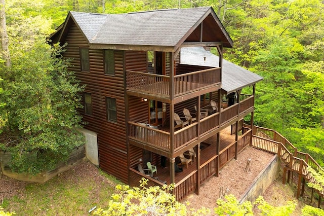 rear view of property featuring stairway, log veneer siding, a shingled roof, and a forest view