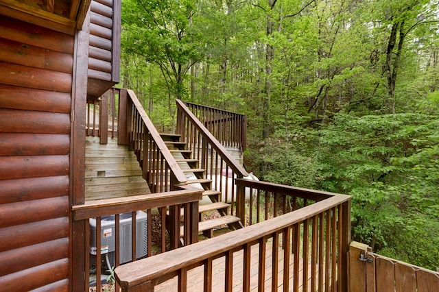 wooden terrace featuring stairs and a view of trees