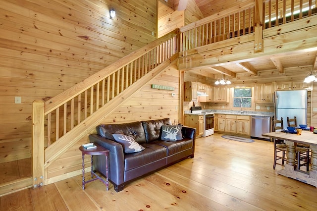 living area with wood walls, stairs, and a notable chandelier