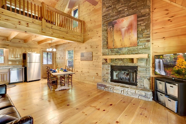 living room featuring wooden walls, beamed ceiling, a chandelier, and light wood-style floors