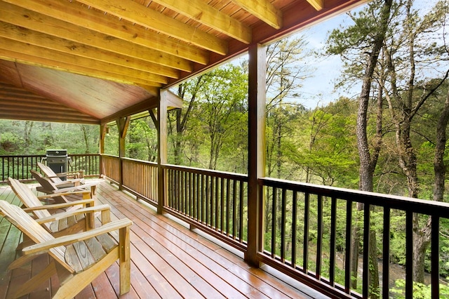 wooden deck with a wooded view and a grill