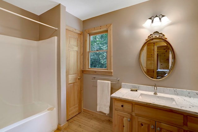 full bathroom featuring baseboards, shower / washtub combination, wood finished floors, and vanity