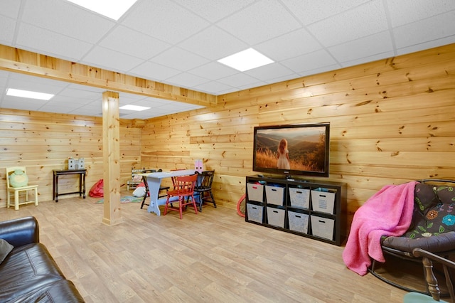 living area with wood walls, a paneled ceiling, and wood finished floors