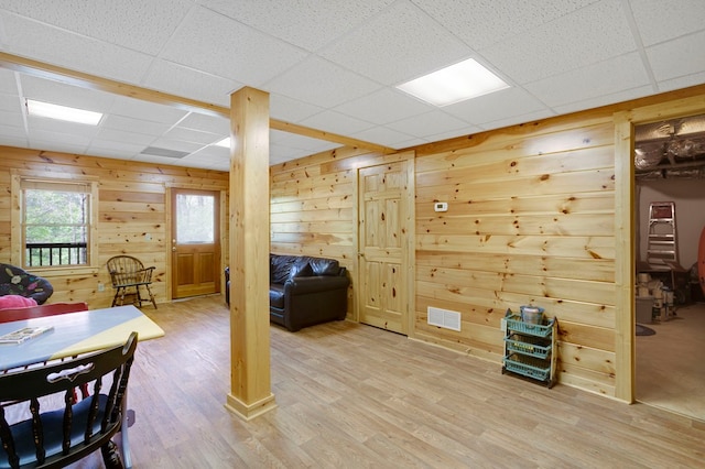 interior space featuring visible vents, wood walls, light wood-style flooring, and a paneled ceiling