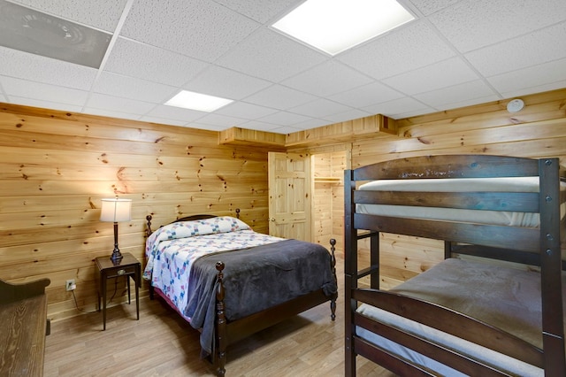 bedroom with wood walls, a paneled ceiling, and wood finished floors