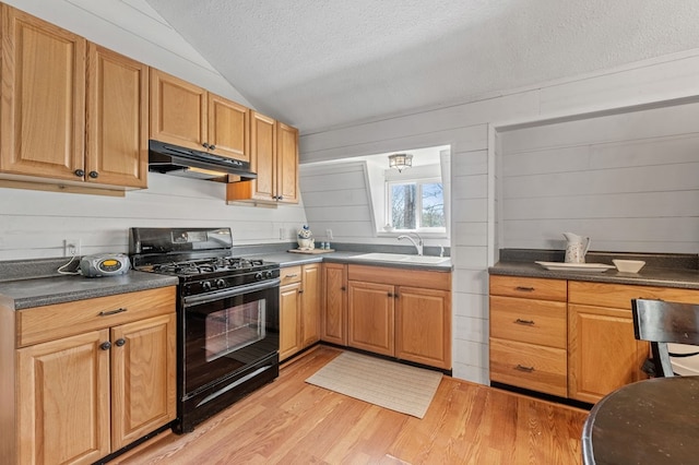 kitchen featuring black gas range oven, sink, light hardwood / wood-style floors, vaulted ceiling, and a textured ceiling