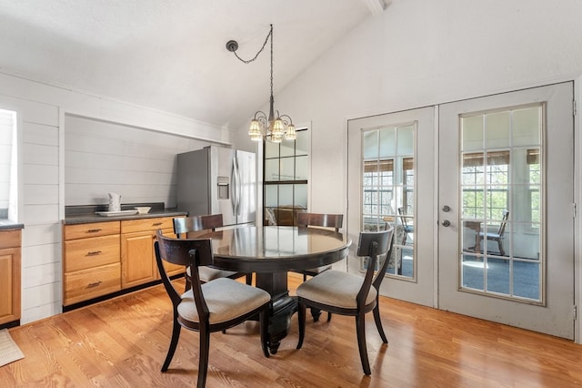 dining area with high vaulted ceiling, french doors, light hardwood / wood-style floors, and a chandelier