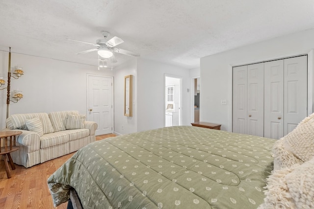 bedroom with ceiling fan, a closet, light hardwood / wood-style flooring, and a textured ceiling