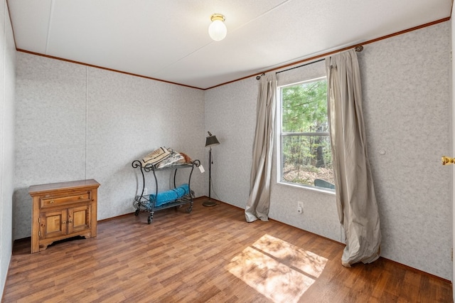 living area featuring a healthy amount of sunlight, light wood-type flooring, and crown molding