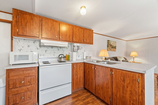 kitchen with dark hardwood / wood-style floors, kitchen peninsula, white appliances, sink, and a textured ceiling